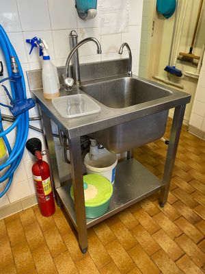 a stainless steel sink in a kitchen with a hose on the wall