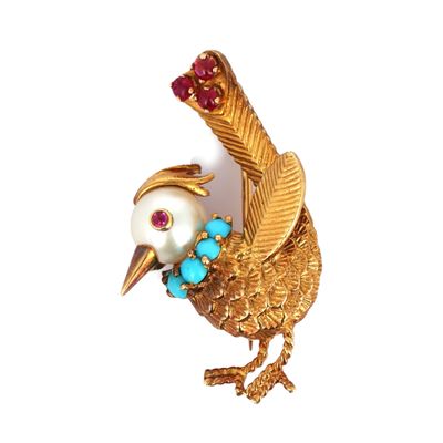 une image représentant une broche en forme d'oiseau en or, ornée de pierres turquoise et rouges