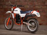 a white and orange dirt bike parked in front of a brick wall