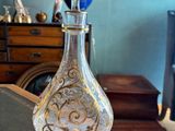 une bouteille en verre posée sur une table, sur laquelle est posée une lampe