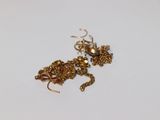 un collier et des boucles d'oreilles en or posés sur une assiette blanche