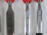 six knives are lined up on a table with a red handle
