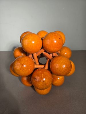 une sculpture orange composée de boules en bois posée sur une table