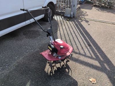 a small tiller on the ground next to a white van