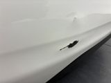 a close up of a white car with a hole in the side of it