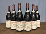 six bottles of red wine are lined up on a wooden table