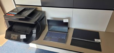 une imprimante et un ordinateur portable posés sur un bureau dans une pièce