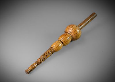 un vieux bâton en bois dont le manche est sculpté, sur une surface grise