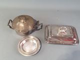 un plat en argent avec un couvercle en argent, à côté d'un plat en argent avec un couvercle en argent