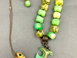 collier, bracelet et bague avec des perles vertes et jaunes sur un fond gris