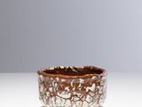 un bol marron et blanc posé sur une table