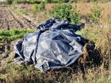 une bâche noire posée par terre à côté d'un champ