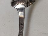 a silver spoon with a spoon handle on a white surface