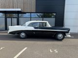 an old black and white car parked in front of a building