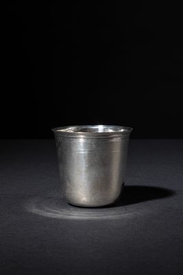 a silver cup sitting on a black surface with a black background