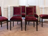 quatre chaises rouges dans une pièce où se trouve un radiateur blanc