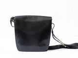 a black leather shoulder bag with a strap on a white background