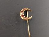 an image of a gold brooch with red and white stones on it