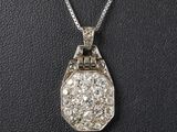 a white gold and diamond pendant on a black leather surface