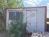 a rusted out building next to a fence and a trash can