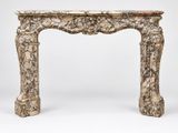 un encadrement de cheminée ancien en marbre, orné d'un motif sculpté
