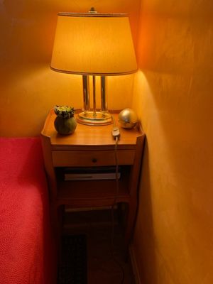 une petite table sur laquelle est posée une lampe, à côté d'un lit