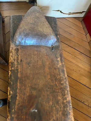 un banc en bois avec une assise en métal posé sur un plancher en bois