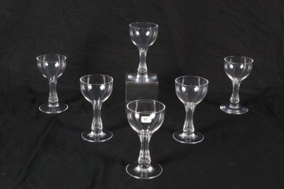 six clear wine glasses are lined up on a black background