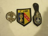 trois insignes sont posés sur un fond blanc, avec une poignée noire