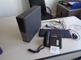 un ordinateur de bureau posé sur un bureau, à côté d'une calculatrice et d'un téléphone
