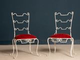 une paire de chaises en fer forgé blanc avec des coussins d'assise en velours rouge