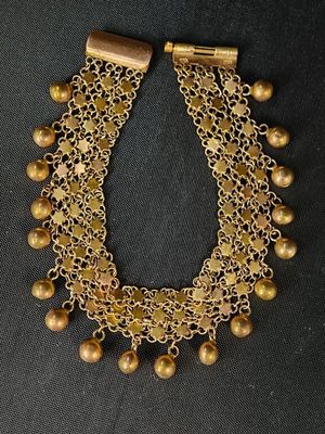un collier en or orné de clochettes et de perles sur fond noir