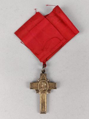 une image représentant une médaille ornée d'une croix, suspendue à un ruban rouge