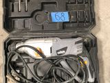 a tool in the case that is sitting on the floor next to a pair of shoes
