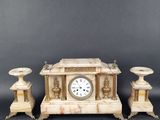 une image représentant une horloge posée sur une table, à côté de deux bougies
