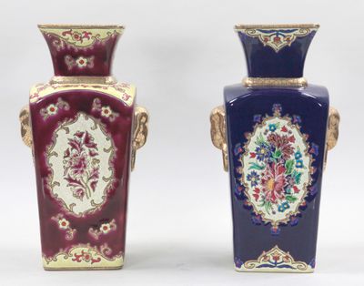 Deux vases ornés de motifs floraux sont posés côte à côte sur une surface blanche