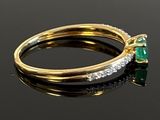 an image of a close up of a gold ring with a green and white diamond