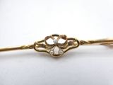 a close up of a gold tie bar with a diamond in the center