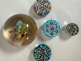 cinq aimants en verre de couleurs différentes sur une surface blanche