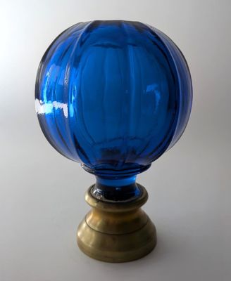 un vase en verre bleu avec un socle doré posé sur une table