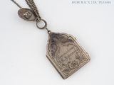 un collier en argent orné d'un livre, posé sur une surface blanche