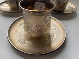 a silver cup and saucer on a silver plate