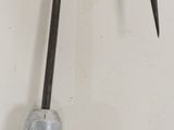 a metal hook with a black handle on a white wall