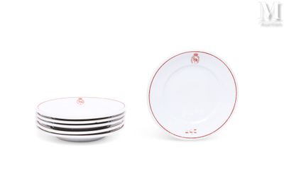 quatre assiettes blanches à bord rouge sont empilées les unes sur les autres