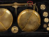 a gold scale with a pair of scissors next to it