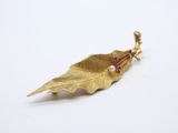 broche en forme de feuille plaquée or, ornée d'une perle
