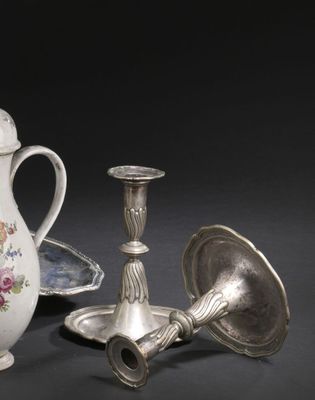 deux bougeoirs en argent et un vase posés sur une table