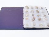 an open book with a bunch of coins in it on a white surface