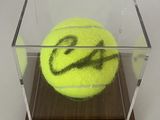 une balle de tennis dans une vitrine sur un socle en bois