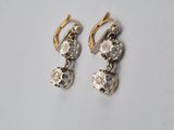 a pair of gold and diamond earrings on a white surface